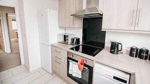 A modern kitchen with a built-in oven, a toaster, a kettle, and a dishwasher. - Sandall Apartment (Doncaster)