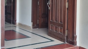 A wooden door with a brass handle, leading to a hallway with a tiled floor.