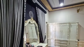A room with a large mirror, a vanity with drawers, and a wardrobe.