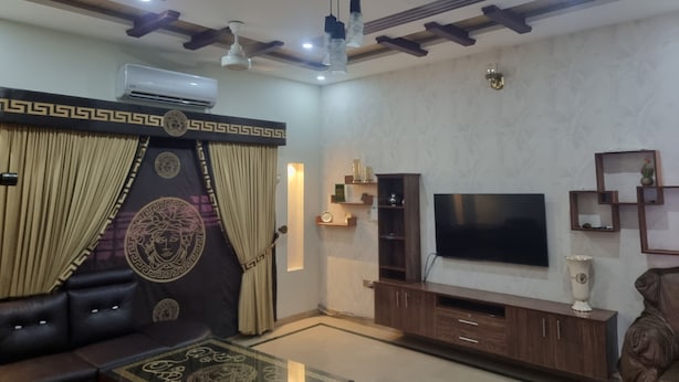 A living room with a sofa, TV, and ceiling fans.