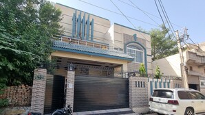 A modern two-story house with a gated entrance, a parked motorcycle, and a white car.