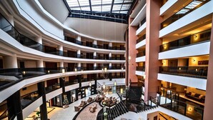 A multi-level atrium with a central staircase, seating areas, and a glass ceiling. - Seven For Life Thermal Hotel (Kusadasi)