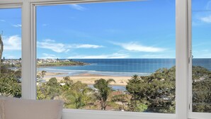 A view from a window overlooking a beach with a clear sky.