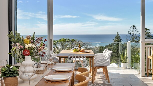 A dining area with a table set for two, overlooking a scenic ocean view.
