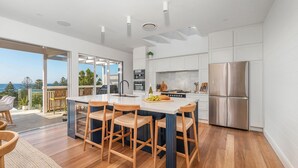 A modern kitchen with a large island, stainless steel appliances, and a view of the ocean.