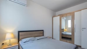 A bedroom with a bed, bedside table with a lamp, and a wardrobe.
