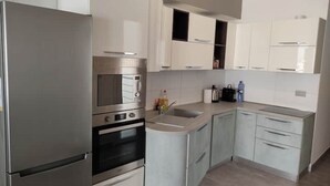 A modern kitchen with stainless steel appliances, white cabinetry, and a central island.