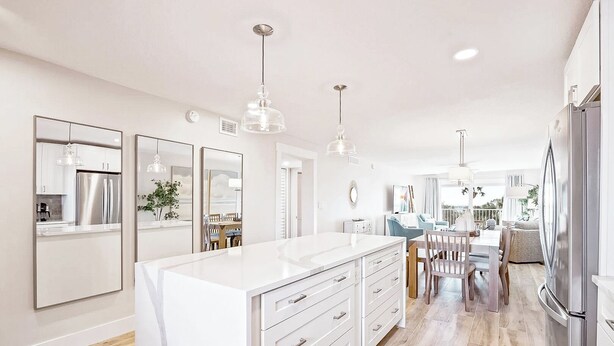 A modern kitchen with a central island, stainless steel appliances, and pendant lighting. - Elegant Coastal-Chic Condo: Pool, Gorgeous Views & Steps to the Pier (Cocoa Beach)