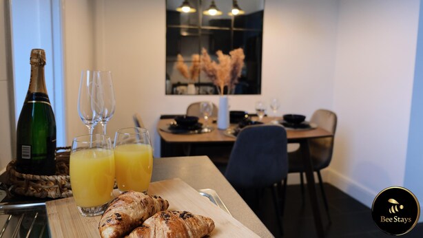 Een ontbijt met croissants, sinaasappelsap en champagne op een houten plank.