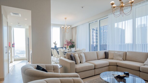Un salon moderne avec un canapé d’angle, des fauteuils et une table basse en verre.