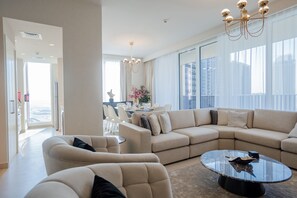 Uma sala de estar moderna com sofá modular, poltronas e uma mesa de centro de vidro.