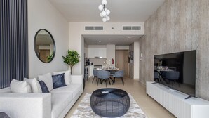 Un salon moderne avec un canapé, une table basse et un téléviseur. Il y a également un coin repas avec des chaises et une table.