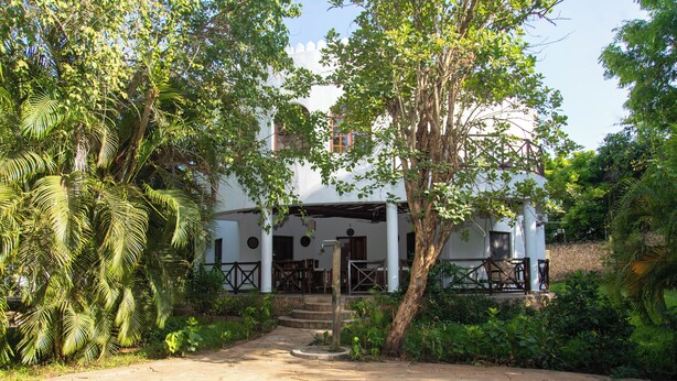 A pool area with a clear view of a white building with columns and a covered patio. - Villa Pundamilia, Private Pool, Free Wifi, Secure (Diani Beach)