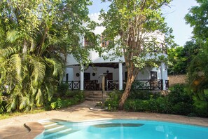 A pool area with a clear view of a white building with columns and a covered patio. - Villa Pundamilia, Private Pool, Free Wifi, Secure (Diani Beach)