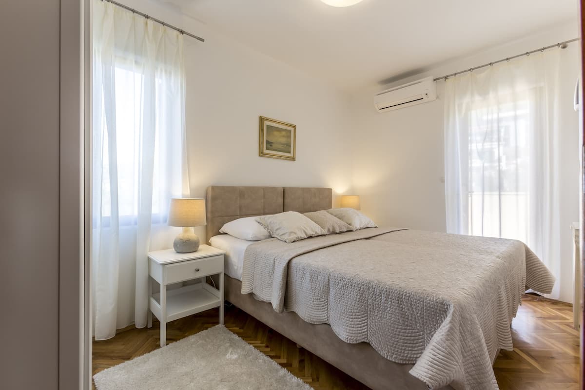 A bedroom with a bed, nightstand, lamp, and a painting on the wall.
