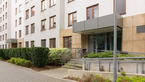 Un bâtiment moderne à la façade plate, doté de nombreuses fenêtres et d’un escalier menant à l’entrée.