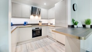 A modern kitchen with white cabinetry, a built-in oven, and a stainless steel countertop. - Week2Week Gosforth apartment w balcony (Newcastle-upon-Tyne)