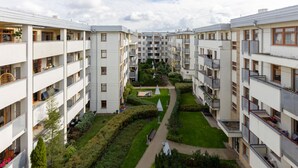Ett modernt bostadskomplex med flera våningar, balkonger och en central innergård med grönska och gångvägar.