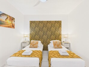 A hotel room with two beds, a patterned headboard, and a painting on the wall.