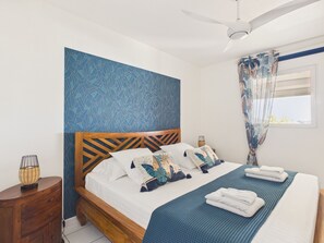 A bedroom with a bed, a nightstand, a ceiling fan, and a window with curtains.