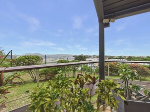 A balcony with a view of a residential area, including houses and a distant mountain range.