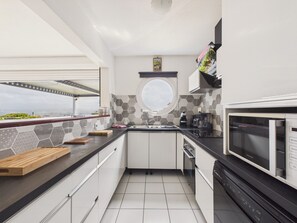 Uma cozinha moderna com vista para a cidade, uma janela redonda e micro-ondas embutido.