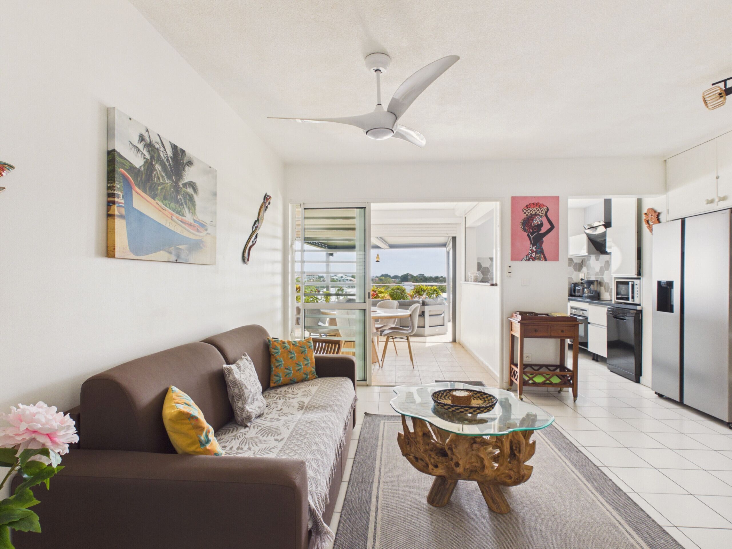 Ein modernes Wohnzimmer mit Sofa, Couchtisch und Kunstwerken. Ein Balkon bietet einen Ausblick.