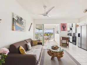 Uma sala de estar moderna com sofá, mesa de centro e obras de arte. Possui uma varanda com vista.