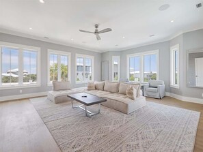 A spacious living room with a large sectional sofa, a coffee table, and a ceiling fan.