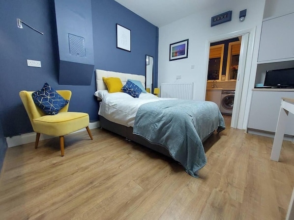A bedroom with a bed, a chair, a radiator, and a TV.