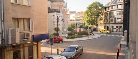 A street view with parked cars, buildings, and a yellow taxi.