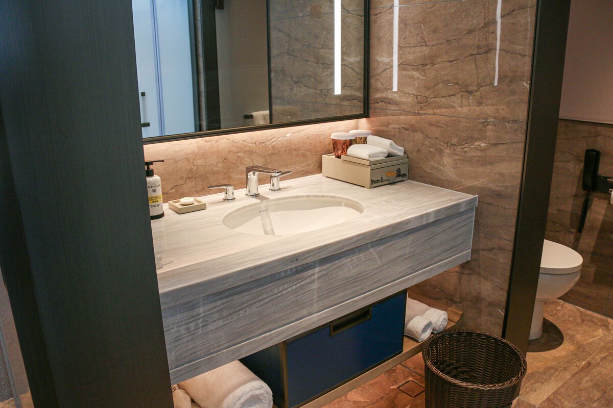 Ein modernes Badezimmer mit einem мраморной раковиной, einem großen Spiegel und einer Toilette.