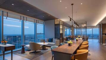 Un interior moderno con una larga mesa de comedor, asientos cómodos y ventanas amplias que ofrecen vistas de la ciudad.