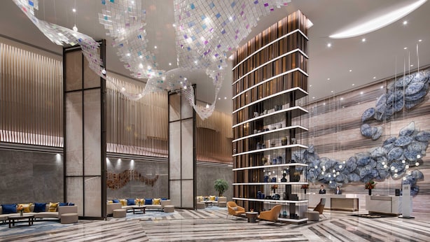 A modern lobby with a central seating area, a reception desk, and a unique ceiling design. - Pullman Huai’an (Huai'an)