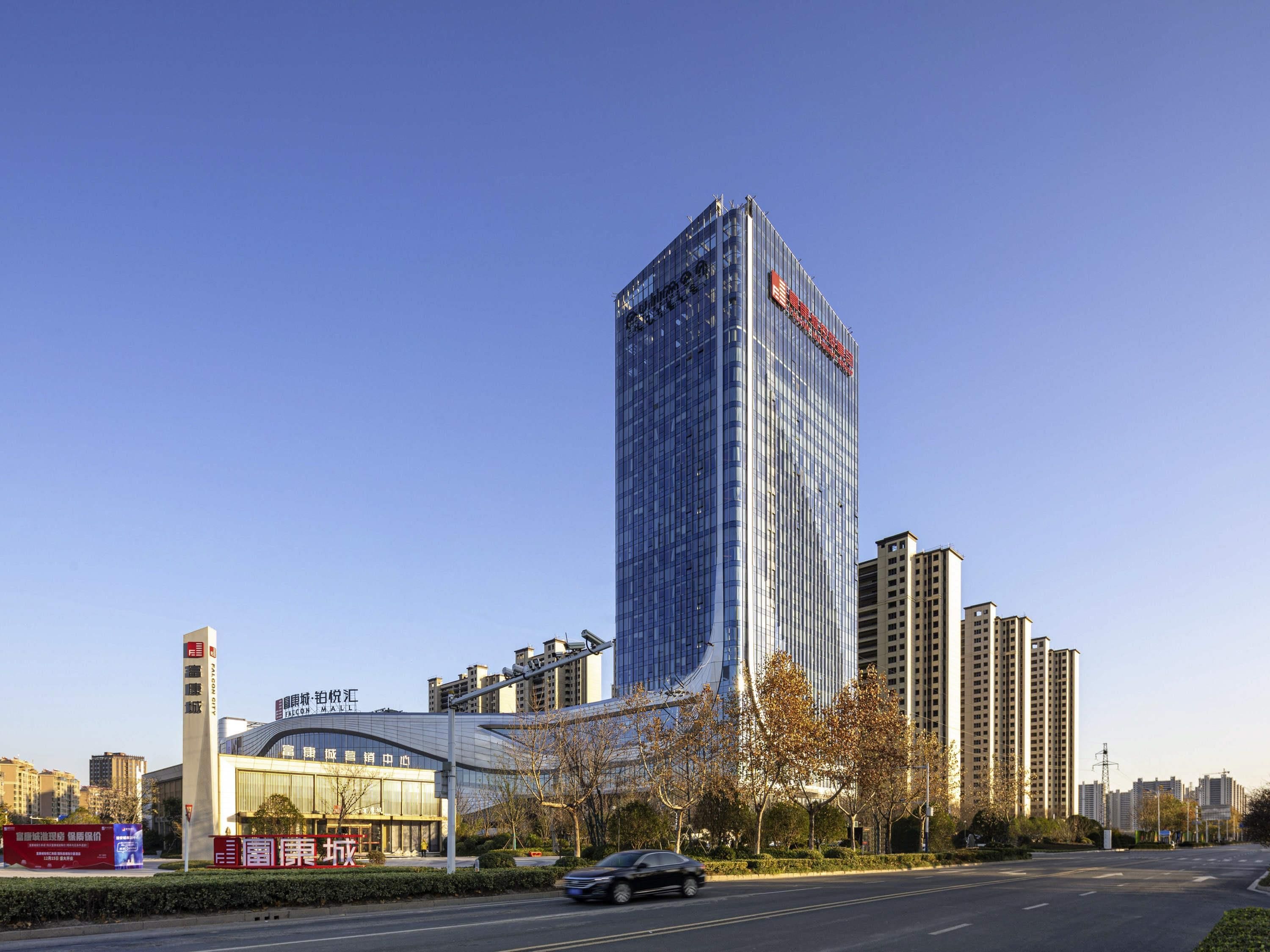 A tall modern building with a glass facade, adjacent to a commercial building with signage.