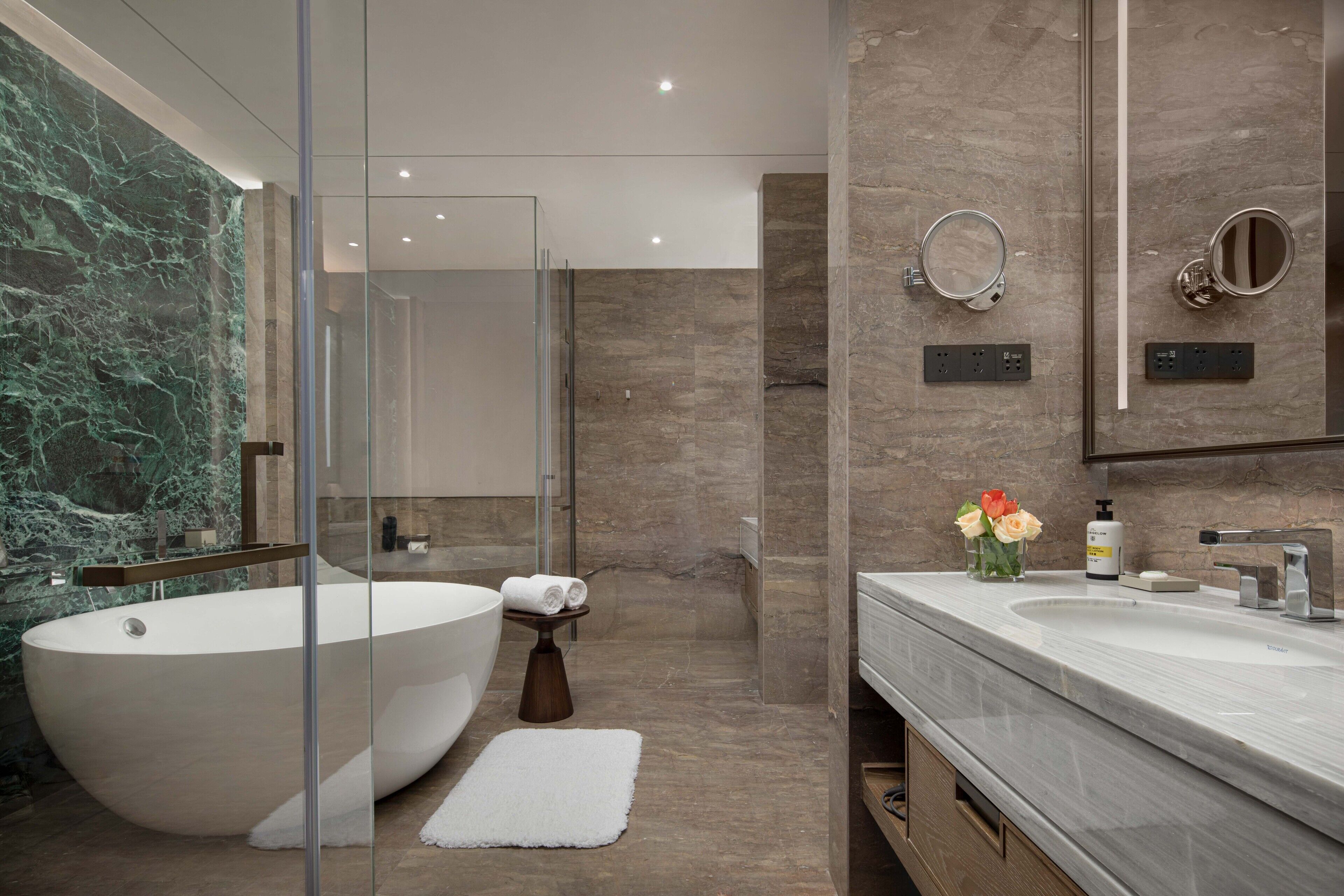 A modern bathroom with a freestanding bathtub, a glass-enclosed shower, and a vanity with a mirror.