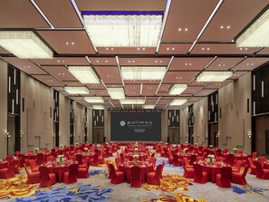 A large conference room with tables set for a formal event, a large screen displaying the hotel name, and a modern chandelier. - Pullman Huai’an (Huai'an)