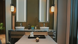 A modern spa room with a massage table, two sinks, and a large mirror. - Pullman Huai’an (Huai'an)