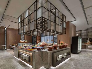 A modern hotel lobby with a central buffet area, marble flooring, and a high ceiling with a geometric glass structure. - Pullman Huai’an (Huai'an)