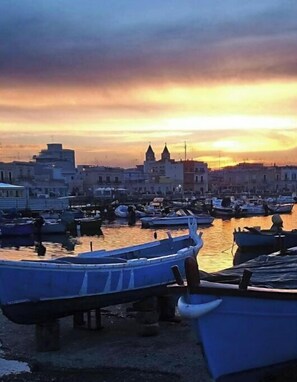 A harbor with boats docked and buildings in the background during sunset.