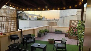 A rooftop patio with outdoor furniture, potted plants, and string lights. - La Piccola Terrazza - Santo Spirito well connected with Bari (Bari)