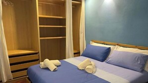 A bedroom with a bed, blue bedding, a wooden wardrobe, and a white curtain. - La Piccola Terrazza - Santo Spirito well connected with Bari (Bari)