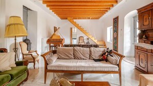 A spacious living room with a wooden ceiling, a grand piano, a staircase, and a traditional wooden cabinet. - Serenity Villa Retreat in Pidasos (Pylos-Nestoras)
