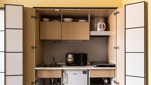 Une cuisine de taille réduite, avec des meubles de rangement en bois, un petit réfrigérateur et un four à micro-ondes.