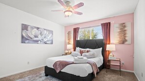 A bedroom with a bed, a ceiling fan, a window with curtains, a painting on the wall, and a bedside table with a lamp. - Ideal for Families & Groups | Theatre | Pet Friendly | Firepit | Spacious (Brighton)