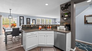 A modern kitchen with white cabinets, a granite countertop, and a coffee-themed decor. - Ideal for Families & Groups | Theatre | Pet Friendly | Firepit | Spacious (Brighton)