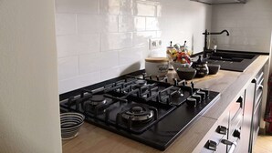 Une cuisine moderne avec des murs recouverts de carreaux blancs, une cuisinière noire et des appareils électroménagers en acier inoxydable.