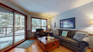 A cozy living room with a sofa, armchair, and a wooden coffee table. - Aspen #120 Prime Ski-in Ski-out Location! Pool, Hot tubs, BBQ, sleeps 6 (Whistler)