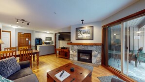 A modern living room with a fireplace, a dining area, and a kitchen. - Aspen #120 Prime Ski-in Ski-out Location! Pool, Hot tubs, BBQ, sleeps 6 (Whistler)