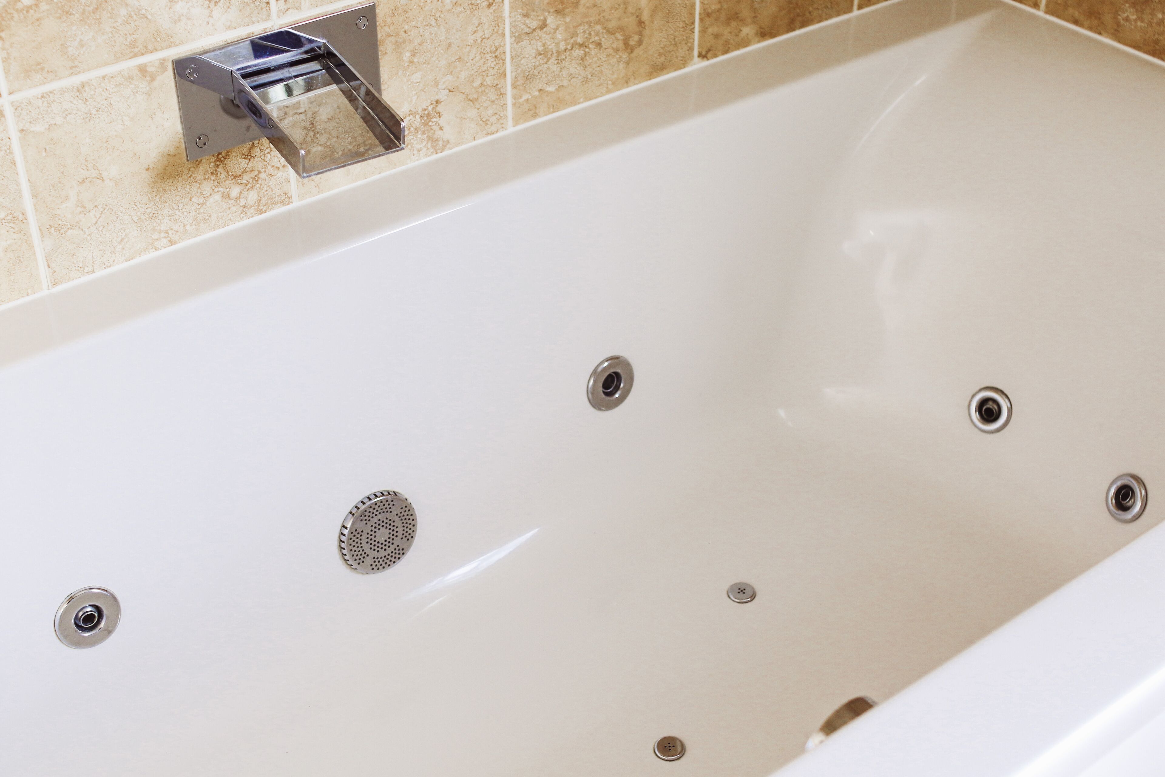 A bathtub with a chrome faucet and a drain.